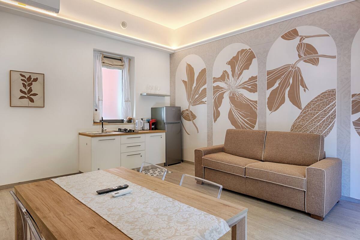 Ein modernes Wohnzimmer mit Sofa, Esstisch und Küchenbereich.