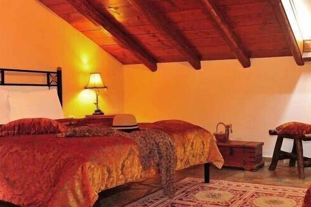 A cozy bedroom with two beds, a wooden ceiling, and a skylight.