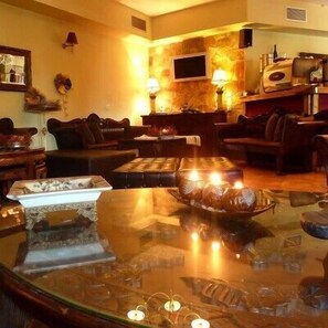 A cozy living room with a glass coffee table, leather sofas, and a fireplace. - Archontiko Fiamegou (Xylokastro-Evrostina)