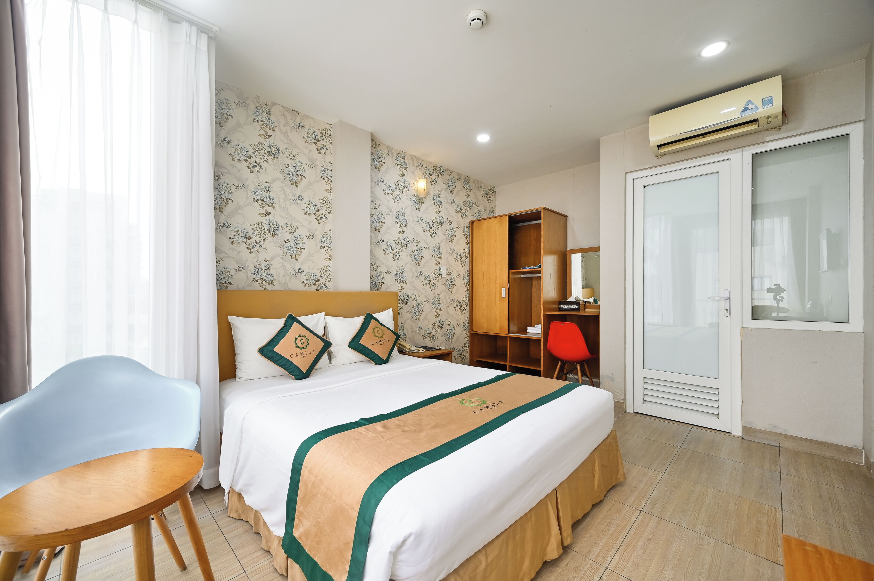 Ein Hotelzimmer mit Bett, Schreibtisch, Stuhl, Kleiderschrank und Klimaanlage.