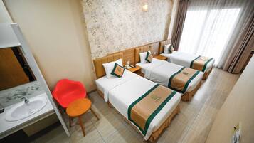 A hotel room with two beds, a bathroom, and a red chair.