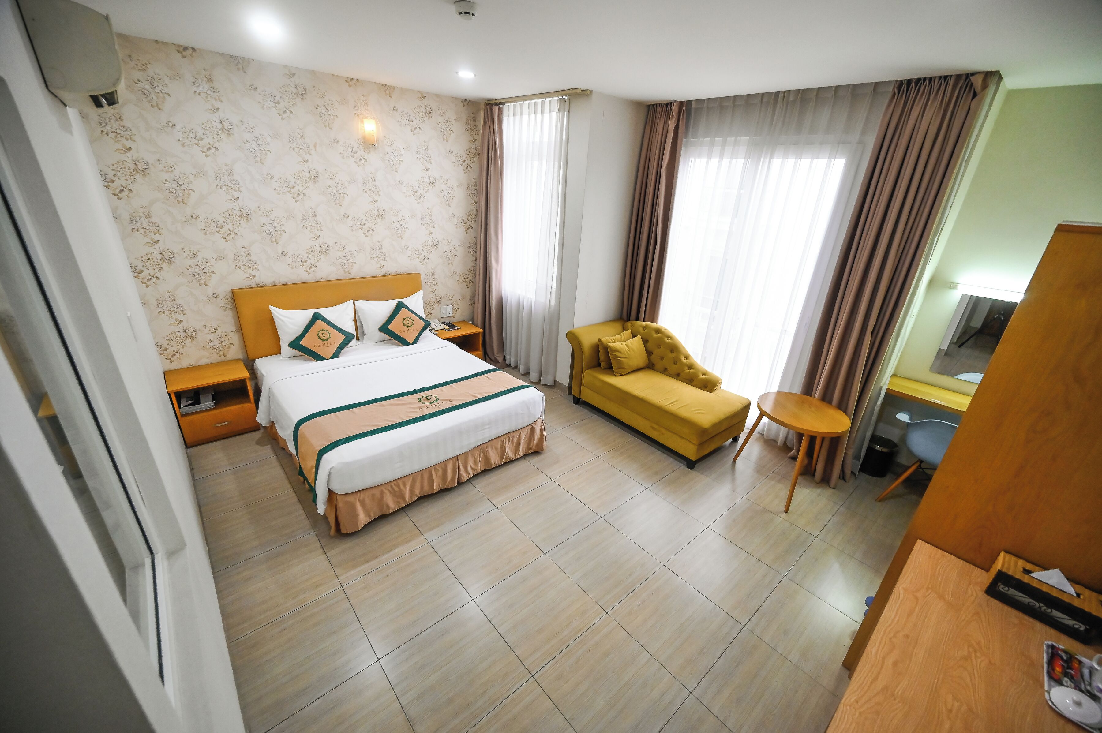 A hotel room with a bed, a sofa, a desk, and a chair.