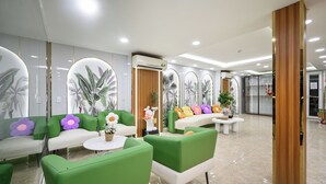 A modern reception area with green and white seating, decorative plants, and a wooden panel wall.