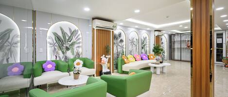 A modern reception area with green and white seating, decorative plants, and a wooden panel wall.