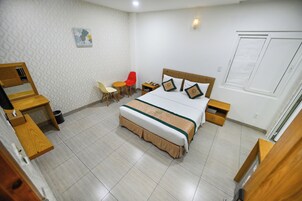 Ett hotellrum med en säng, sängbord, ett skrivbord, en stol och ett litet bord med en stol.