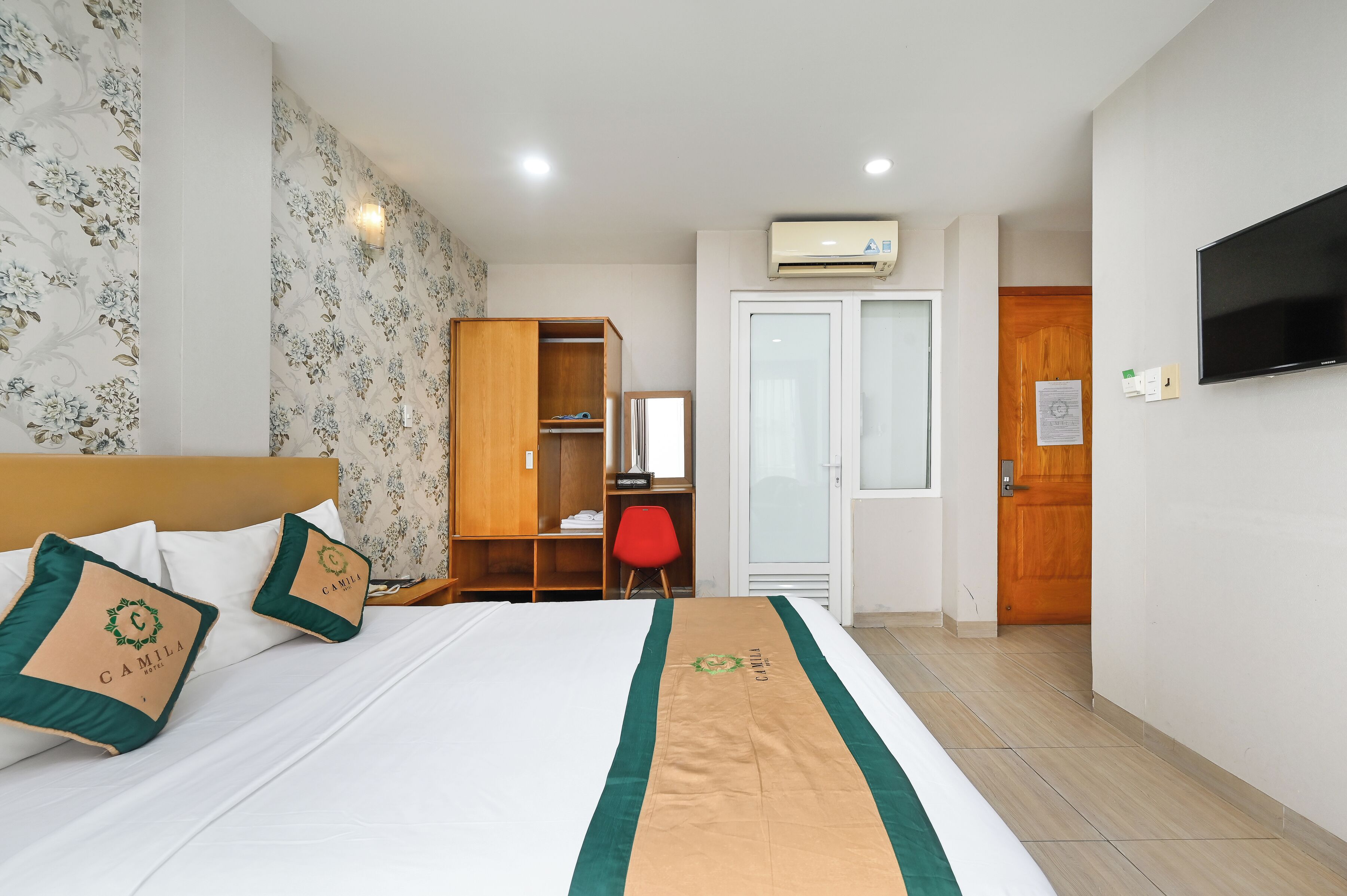 A hotel room with a bed, a wardrobe, a desk, and a television.
