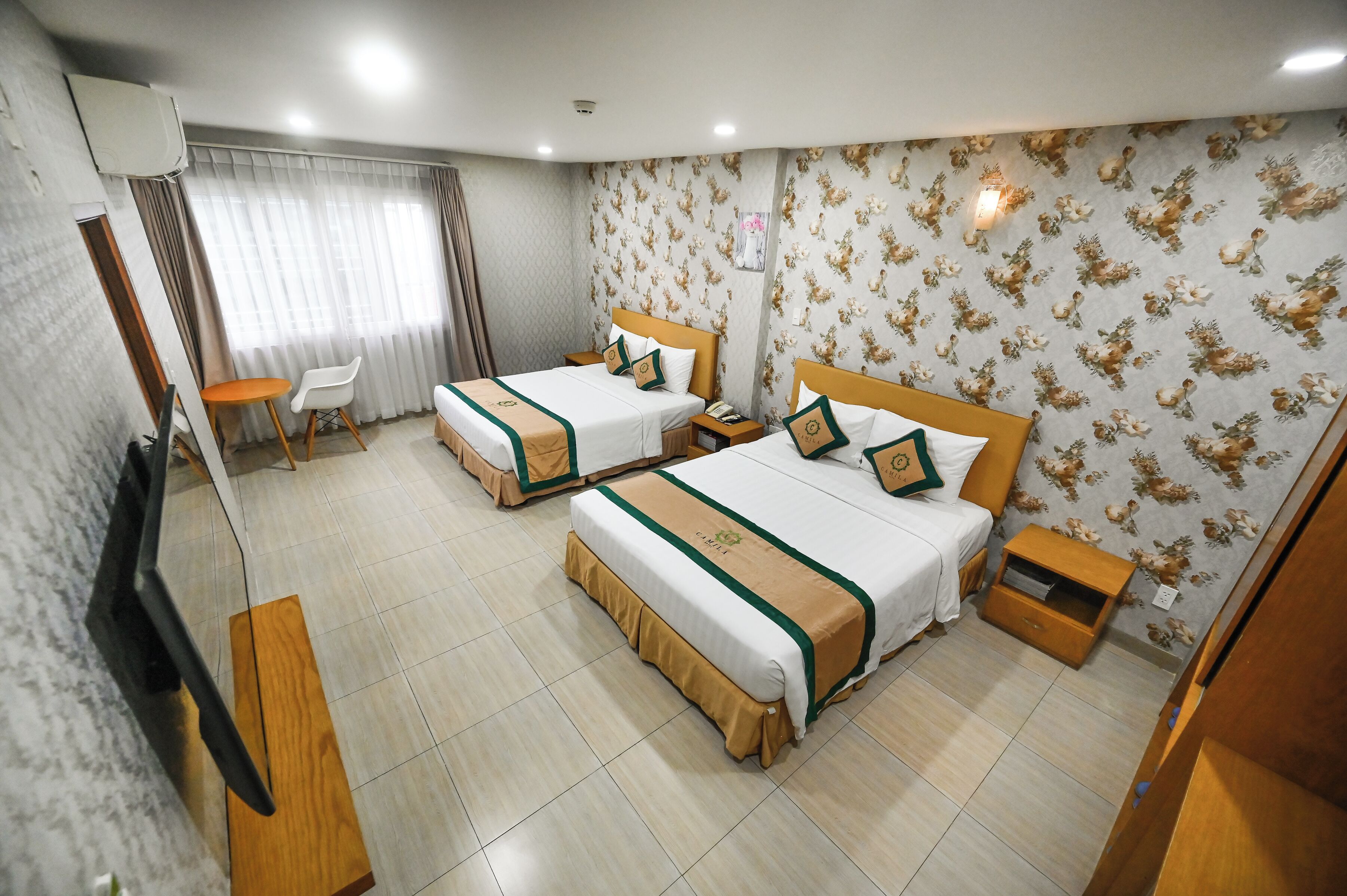 A hotel room with two beds, a TV, a desk, and a chair.