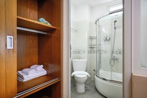 A bathroom with a toilet, a glass-enclosed shower, and a wooden vanity with folded towels.