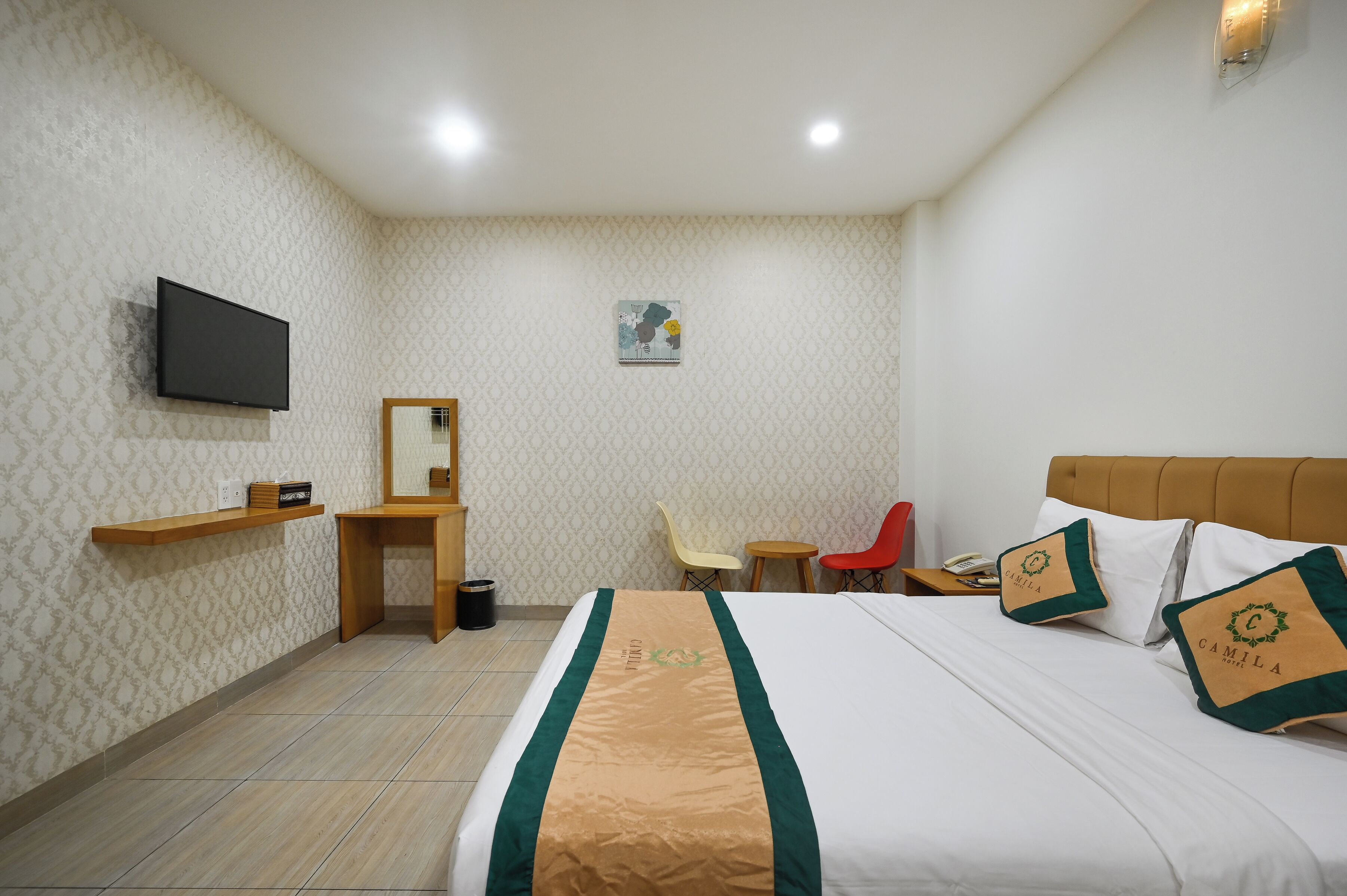 A hotel room with a bed, a TV, a desk, a chair, and a small table.