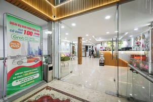 Un hall d’hôtel avec une entrée dotée d’une porte en verre, un comptoir d’accueil et un panneau publicitaire indiquant les services de navette aéroport.