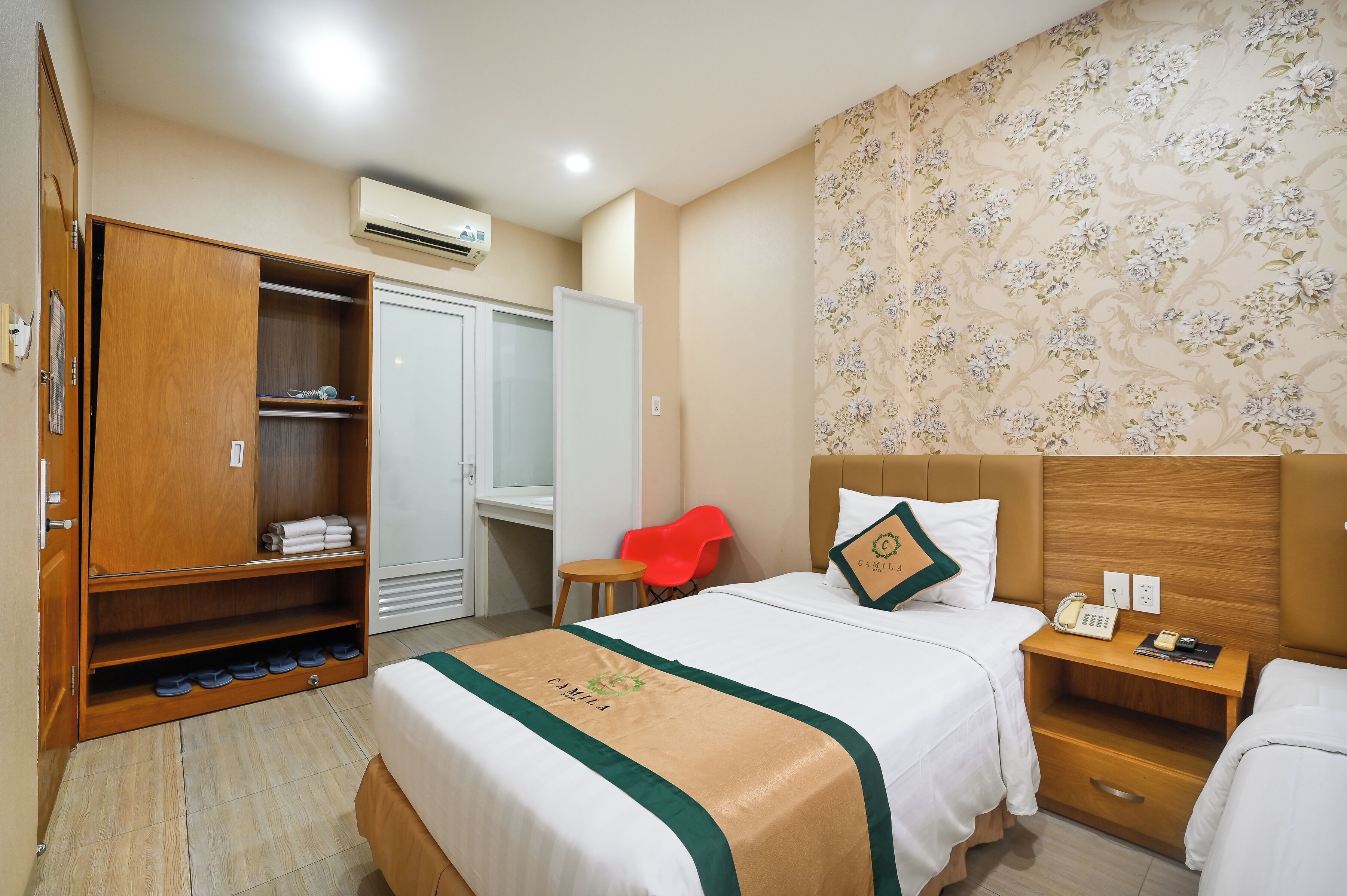 Habitación de hotel con cama, armario, escritorio, silla y baño.