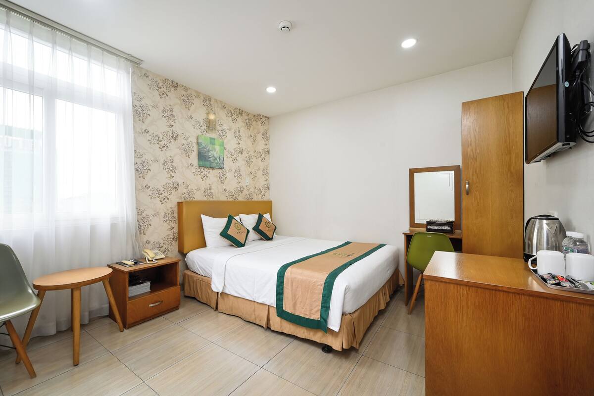A hotel room with a bed, a desk, a chair, a television, and a coffee maker.