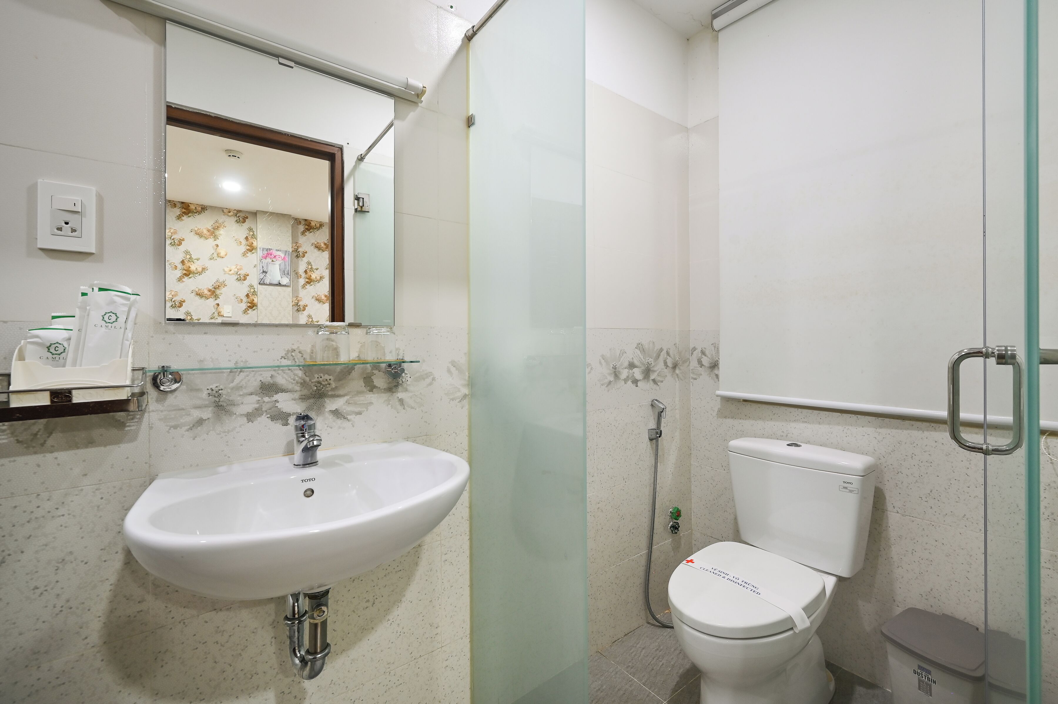 A bathroom with a white sink, a toilet, and a glass shower enclosure.