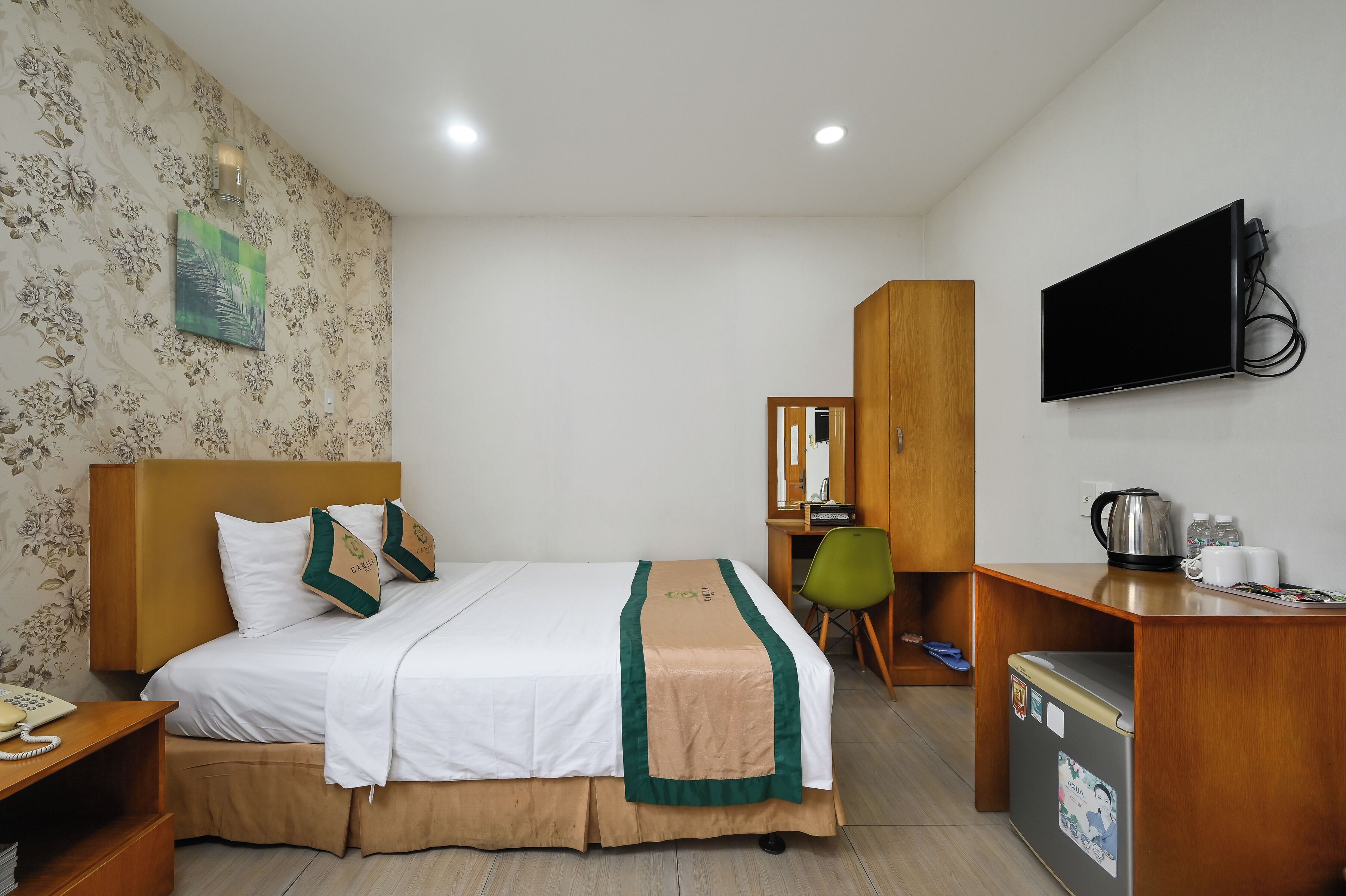 Ein Hotelzimmer mit Bett, Schreibtisch, Fernseher und Kühlschrank.