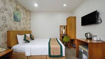 Ein Hotelzimmer mit Bett, Schreibtisch, Fernseher und Kühlschrank.