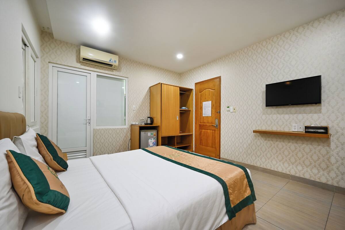 A hotel room with a bed, wardrobe, TV, and a small shelf.