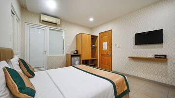 Habitación de hotel con cama, armario, televisor y un pequeño estante.
