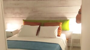 Ein Schlafzimmer mit einem hölzernen Kopfteil, einem Bett mit weißer und blauer Bettwäsche und einem grünen Teppich.
