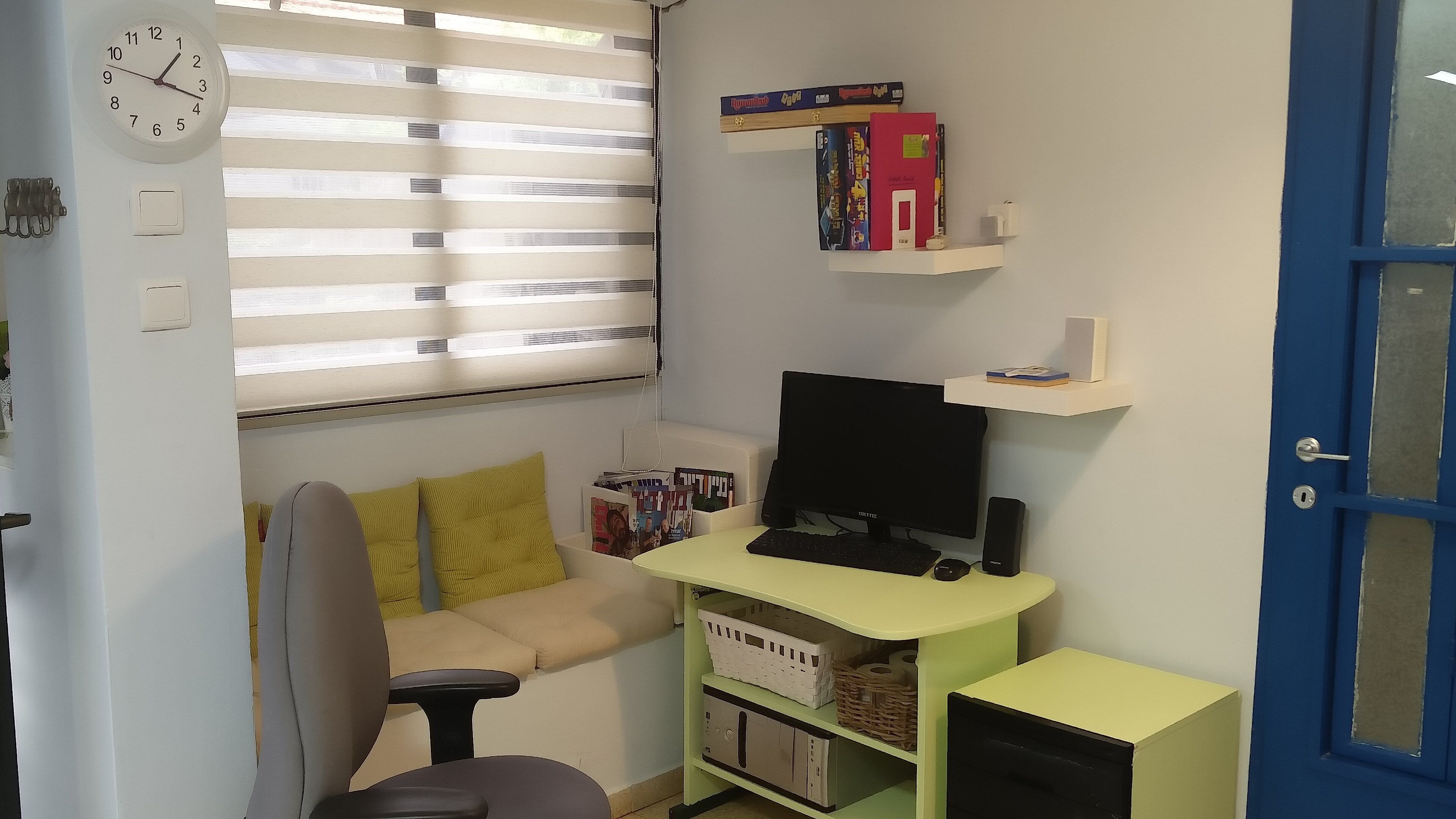 Un pequeño espacio de oficina con un escritorio, computadora y estanterías llenas de libros y archivadores.