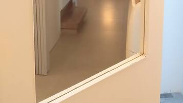 A hallway with a small table and a light source on the wall.
