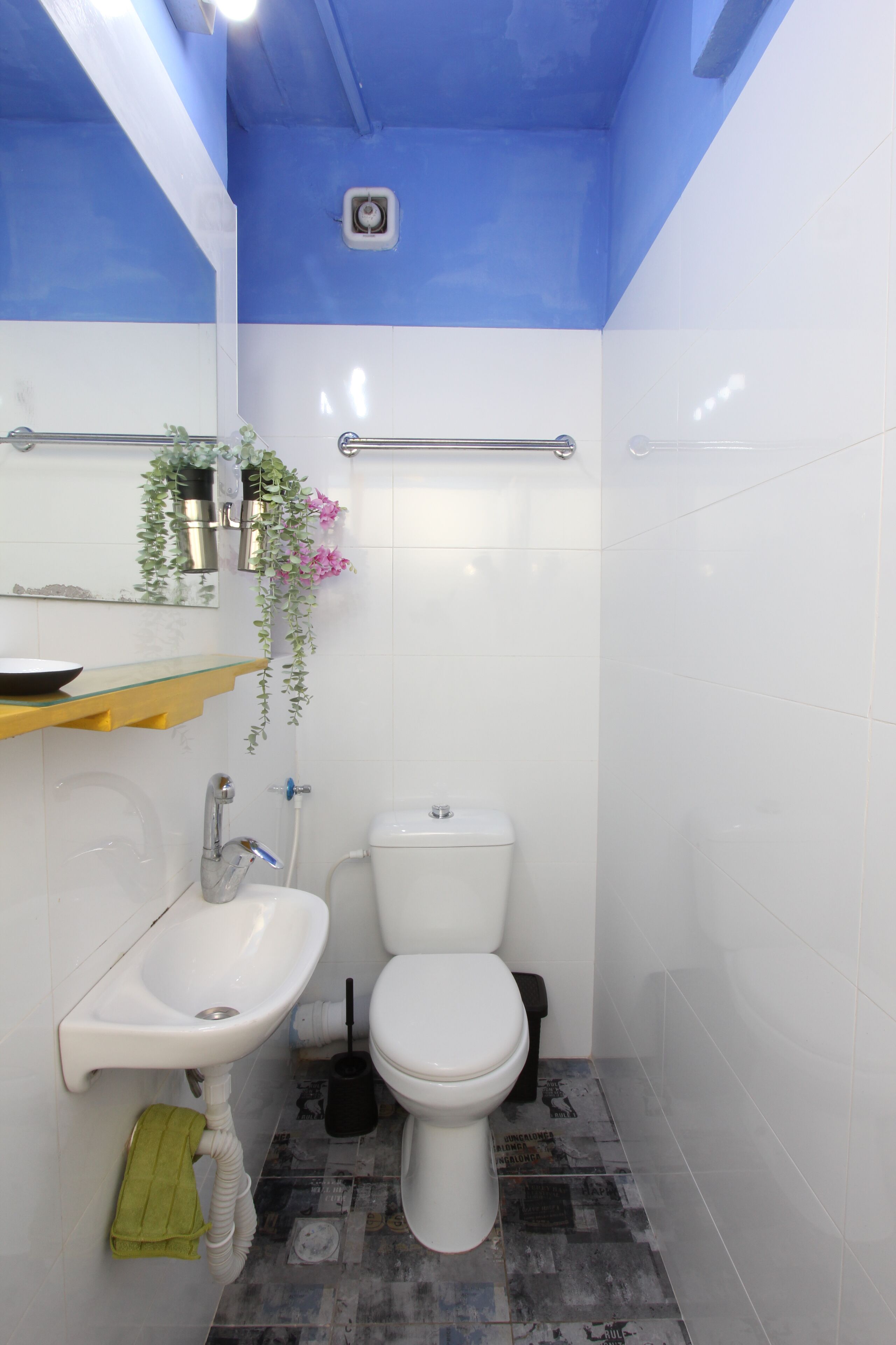 A bathroom with a white sink, toilet, and a blue ceiling.