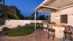Un espace extérieur aménagé avec une table de billard, un bar et des sièges.
