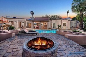 A poolside area with a fire pit, lounge chairs, and a swimming pool. - Ryan's Resort By Signature Vacation Rentals (Scottsdale)