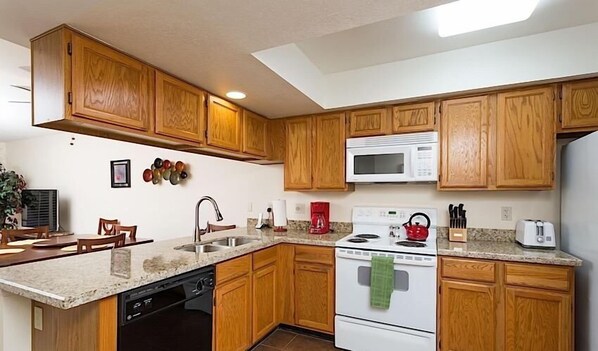 A kitchen with wooden cabinets, a microwave, a stove, and a dishwasher.