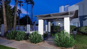 Un bâtiment moderne doté d’un patio couvert, entouré d’un aménagement paysager soigné et de grands palmiers.