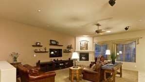 Uma sala de estar com lareira, televisão e ventilador de teto.