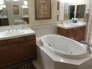 Un baño con dos lavamanos, una bañera y un espejo grande.