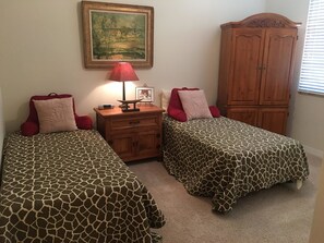 Un dormitorio con dos camas, una mesita de noche, una lámpara, un cuadro y un armario.