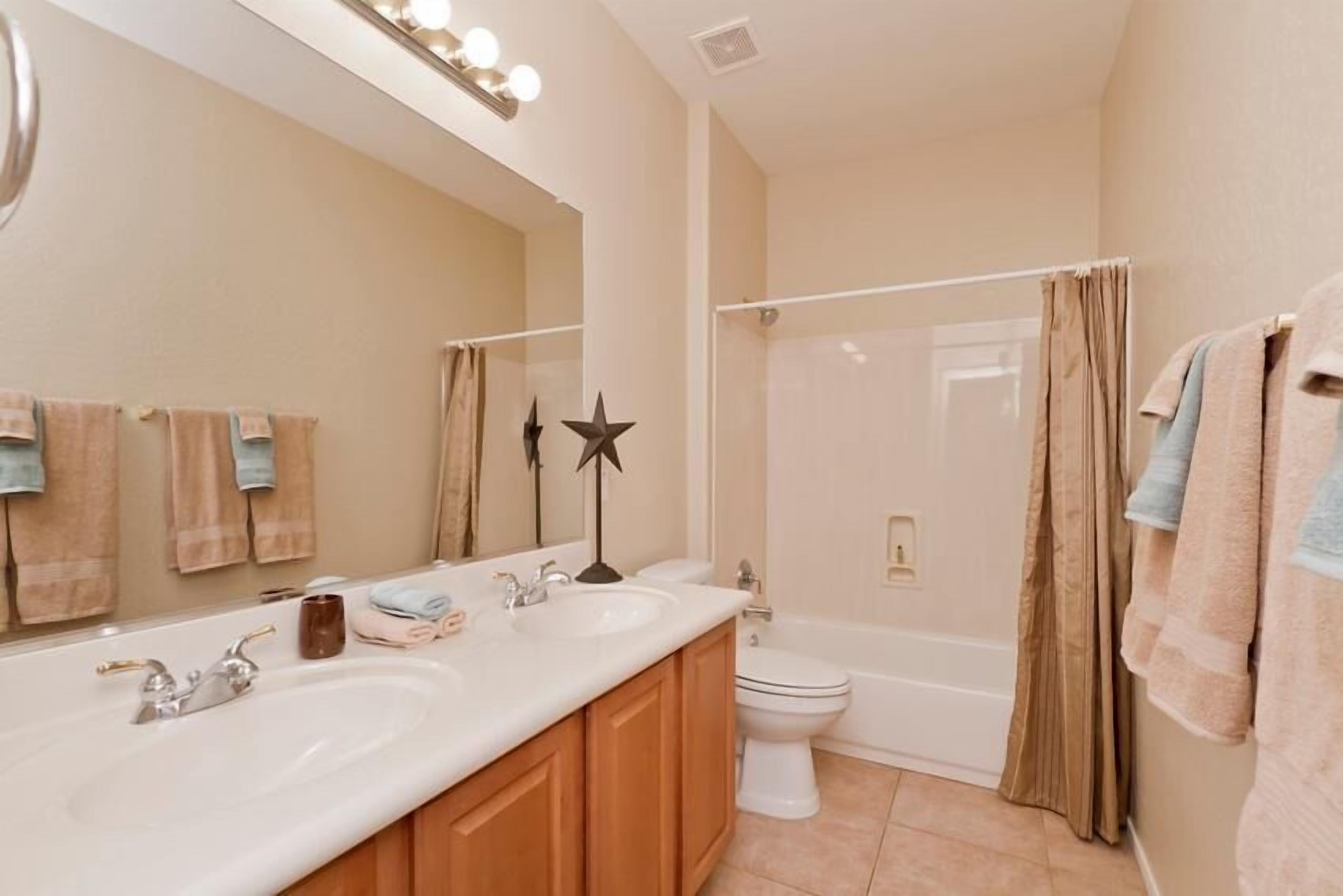 A bathroom with two sinks, a toilet, and a shower.