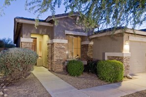 A modern two-story house with a stone facade, a front door, and a garage. - Quail Bluff By Signature Vacation Rentals (Goodyear)