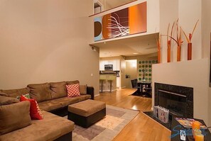 A modern living room with a sectional sofa, a fireplace, and a dining area in the background. - Phoenix Palms By Signature Vacation Rentals (Phoenix)