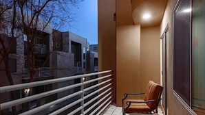 A balcony with a chair, a railing, and a view of buildings. - Phoenix Palms By Signature Vacation Rentals (Phoenix)
