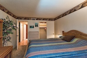 Un dormitorio con cama, mesita de noche, cómoda y planta.