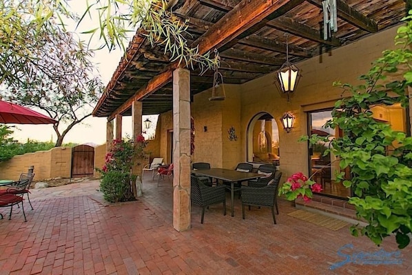 An outdoor patio with a brick floor, wooden pergola, and wicker furniture. - Peak of Perfection By Signature Vacation Rentals (Tucson)