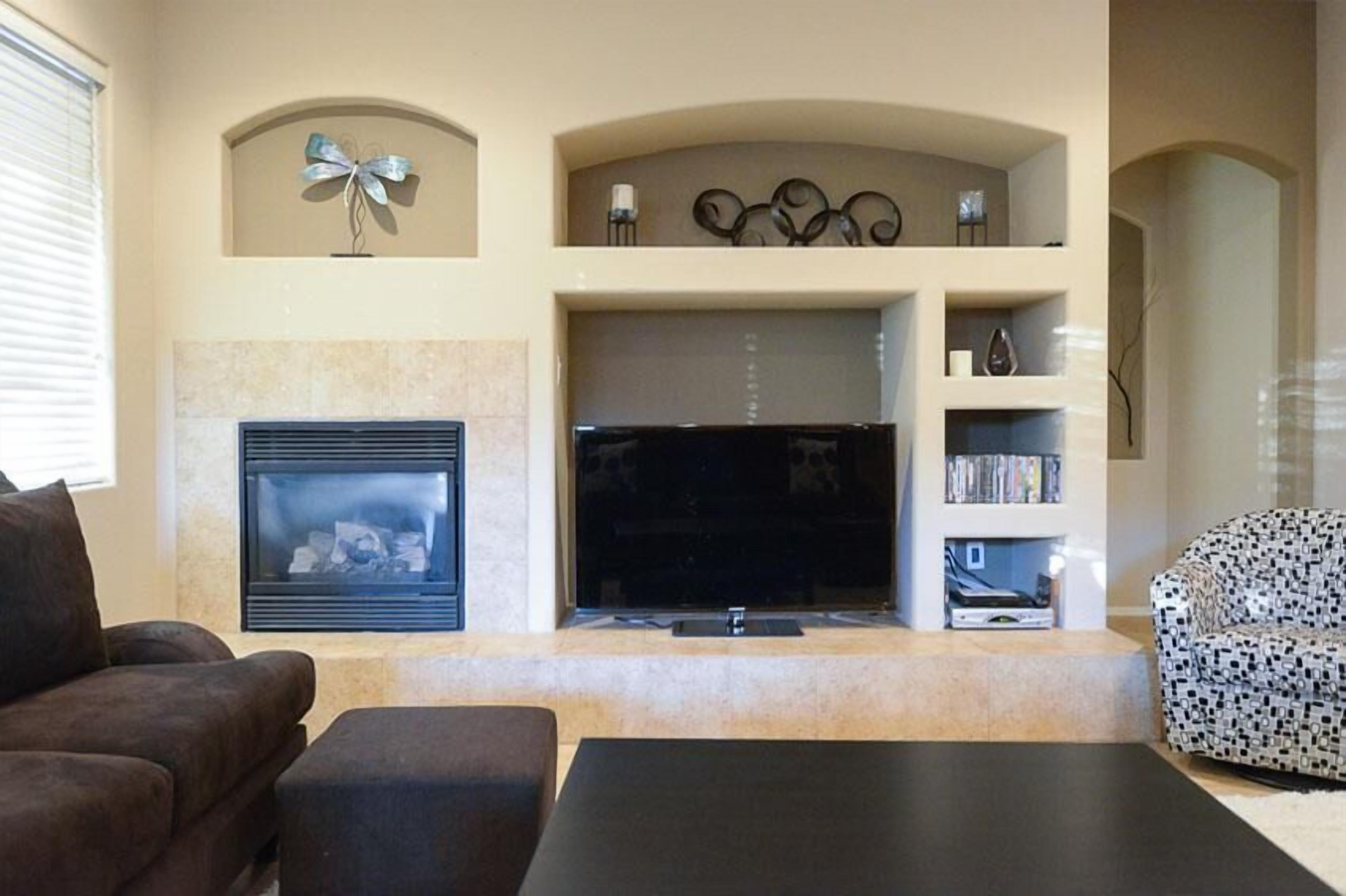 Una sala de estar con chimenea, un televisor de pantalla plana, un sofá y un sillón estampado.