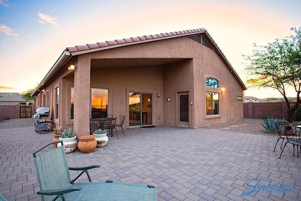A building with a covered patio area, outdoor seating, and potted plants.