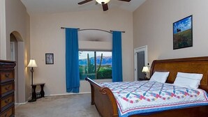 A bedroom with a bed, a nightstand, a lamp, a dresser, a window with curtains, and a ceiling fan. - Scenic Spectacular By Signature Vacation Rentals (Oro Valley)