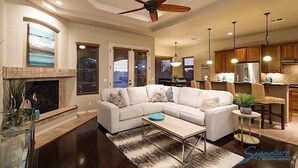A spacious living room with a sectional sofa, a fireplace, and a ceiling fan. - Sail Away By Signature Vacation Rentals (Chandler)