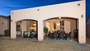 A modern house with a covered patio area featuring outdoor seating and a barbecue grill. - Sail Away By Signature Vacation Rentals (Chandler)