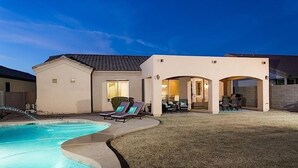 A modern house with a swimming pool, outdoor seating, and a well-lit patio area. - Sail Away By Signature Vacation Rentals (Chandler)