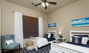A bedroom with two beds, a chair, a ceiling fan, and a window with blinds.