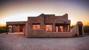Une maison moderne avec un revêtement en stuc, un toit plat, de grandes fenêtres et un patio couvert.