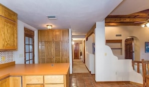 A kitchen with wooden cabinets, a countertop, and a hallway leading to a bedroom. - Saguaro Serenity By Signature Vacation Rentals (Tucson)