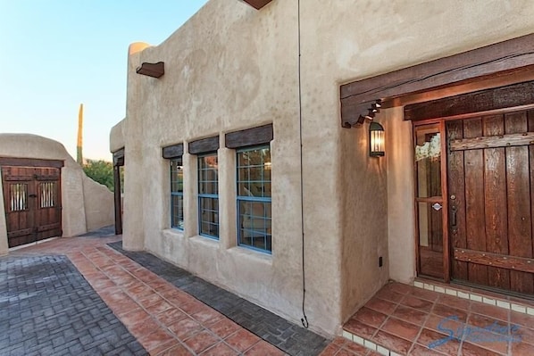 A building with stucco walls, a wooden door, and a tiled entrance. - Saguaro Serenity By Signature Vacation Rentals (Tucson)