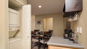 A compact kitchen with a built-in oven, a dining area with a table and chairs, and a coffee station with a coffee maker and cups. - Parktopia By Signature Vacation Rentals (Scottsdale)