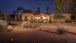 A two-story house with a patio area, surrounded by desert landscaping including cacti and agave plants. - Paradise Retreat - PV622 By Signature Vacation Rentals (Scottsdale)